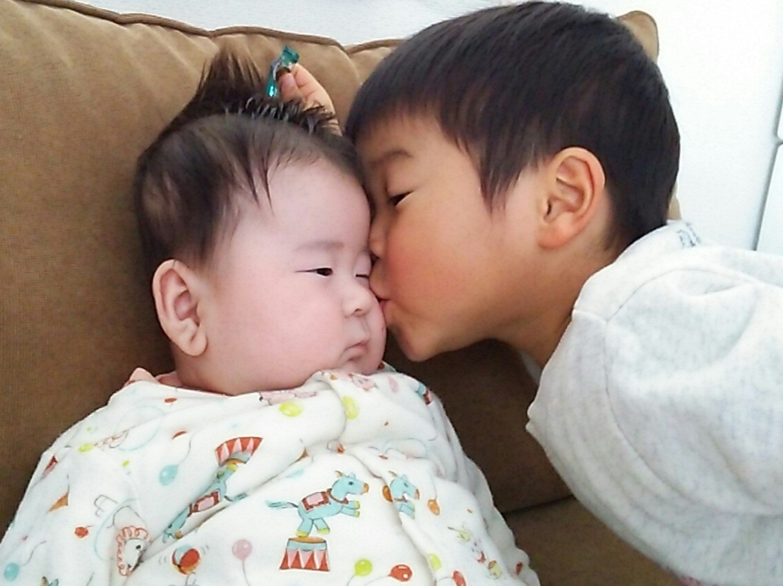 赤ちゃんにキスする子ども